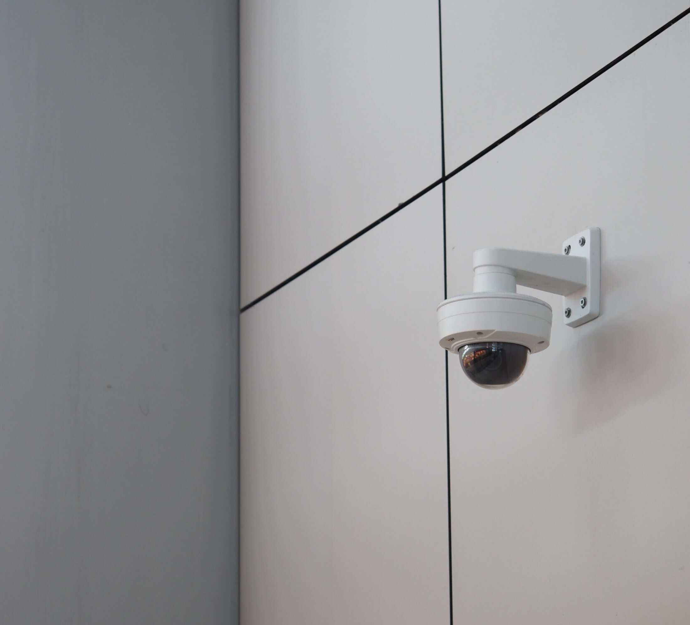 Security Camera Installed on Building Exterior A security camera mounted on the exterior wall of a commercial building, ready for surveillance and security monitoring.