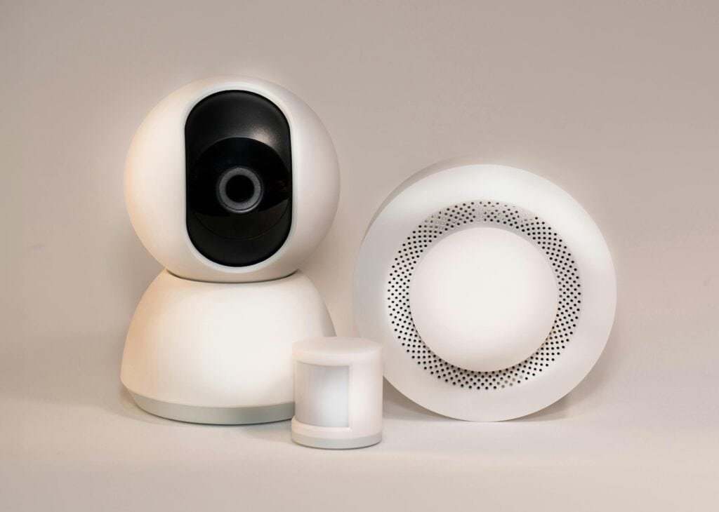 Modern security camera and sensor system for home or business security, featuring a sleek white design and advanced monitoring technology.