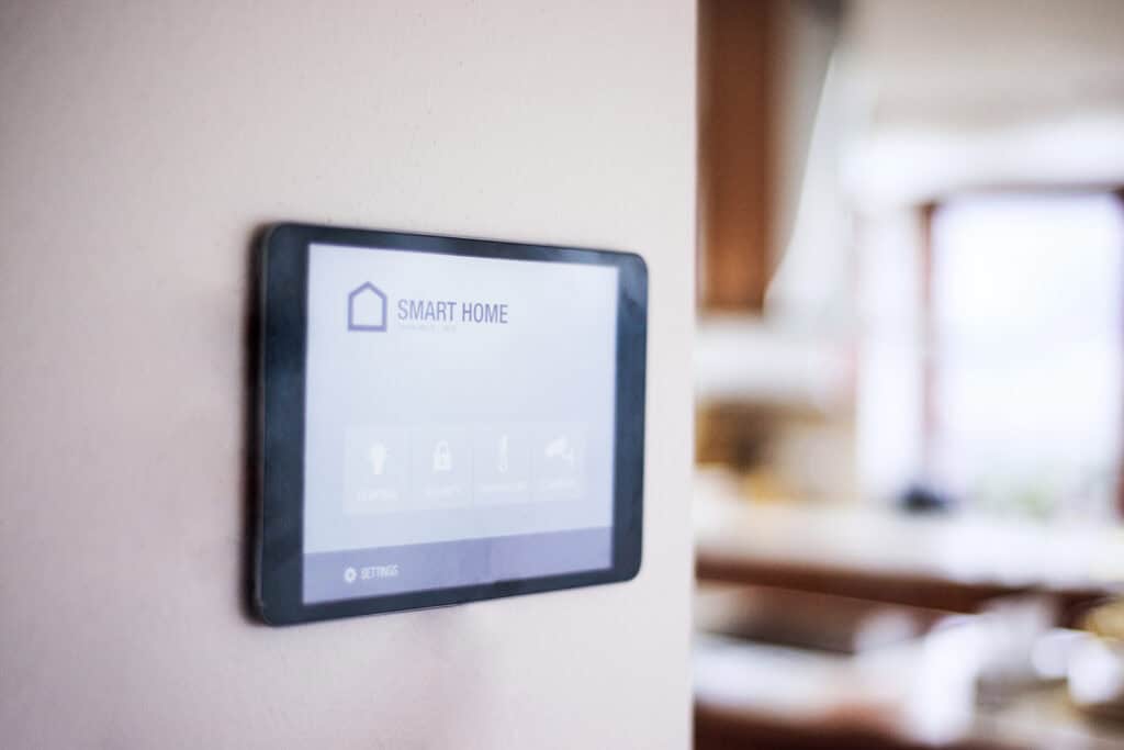 Smart home security touchscreen panel mounted on a wall, used for controlling security cameras and home automation systems.